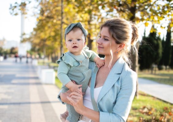 picture of a mum holding a baby with hair and make up on wearing nice clothes