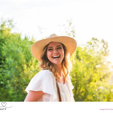 picture of a happy woman outside with nice hair wearing a hat for sun protection